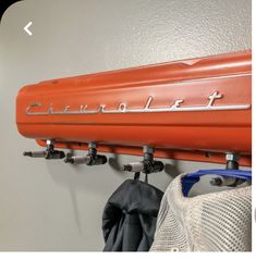 an orange car is hanging on the wall next to a coat rack with two umbrellas