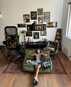 a woman sitting on top of a green couch in a living room next to a window