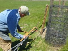 a man in blue shirt and khaki pants working on a fence