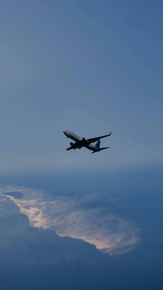 an airplane is flying in the sky with clouds around it and blue skies behind it