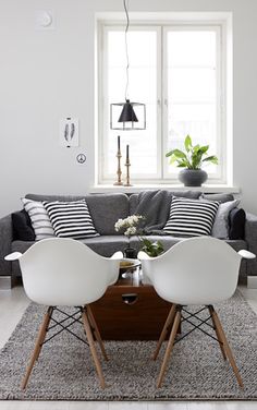 two white chairs sitting next to each other in front of a black and white couch