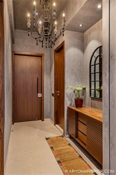 a hallway with a chandelier, mirror and wooden cabinet in the middle is shown