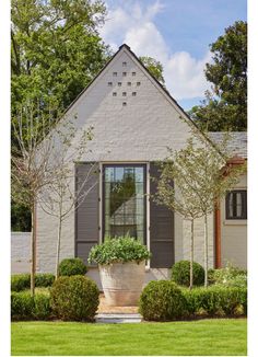 a white brick house with black shutters and green grass in front of the window