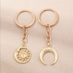 two gold key chains with the sun and moon on them