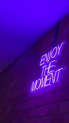 a purple neon sign that says enjoy the moment