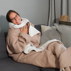 a woman laying on a couch wrapped in a blanket