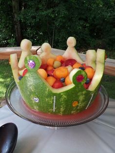 a watermelon boat filled with lots of fruit on top of a glass plate