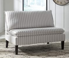 a striped couch sitting on top of a rug in a living room next to a clock