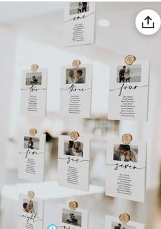 wedding seating cards hanging on the wall in front of a window with photos and text