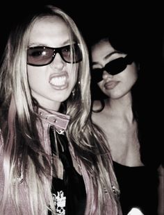 two women wearing sunglasses and one has her tongue out