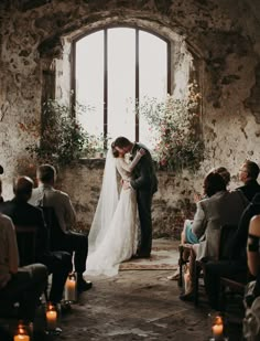 a bride and groom are kissing in front of an open window at their wedding ceremony