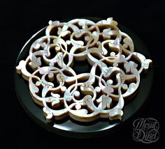 an intricately designed cookie on a black plate with white frosting and icing