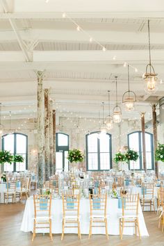 a large room with tables and chairs set up for a wedding reception in front of windows