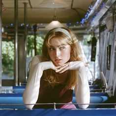 a woman sitting on top of a bus next to a blue table with chairs in front of her