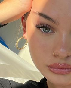 a close up of a woman with blue eyes and gold hoop earrings on her head