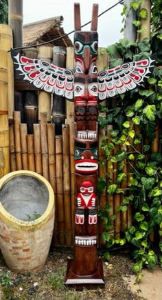 a wooden totema sitting next to a potted plant in front of a bamboo fence