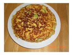 an omelet on a white plate sitting on a wooden table