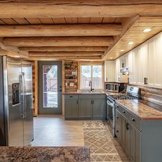 a kitchen with wooden ceilings and granite counter tops, stainless steel appliances and refrigerators