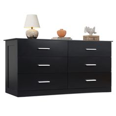 a black dresser with several drawers and a lamp on top