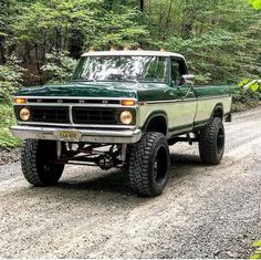 a green pick up truck driving down a dirt road