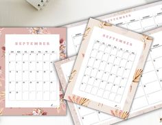 three calendars with floral designs on them sitting next to a pen and pencil holder