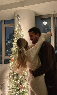 a man and woman standing in front of a christmas tree