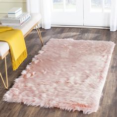 a living room area with hardwood floors and white furniture, including a pink rug on the floor