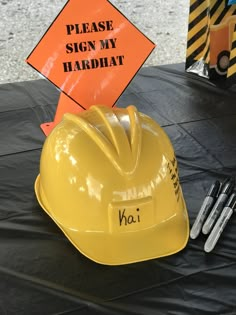 a yellow hard hat sitting on top of a table next to some construction signs and tools