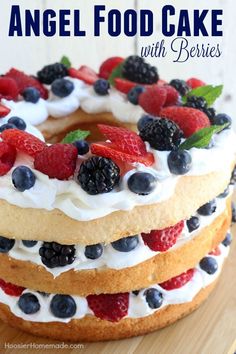 an angel food cake with berries and whipped cream on top is sitting on a wooden table