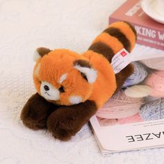 a stuffed animal laying on top of yarn next to a knitting book and ball of yarn