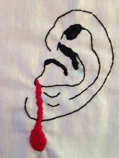 a close up of a piece of cloth with an embroidered face and red thread on it