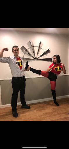 a man and woman dressed up as superheros posing for a photo in front of a clock