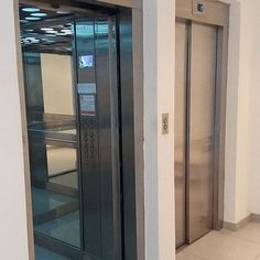 an empty elevator in a building with two doors open on each side and another door closed to the other side