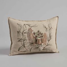 an embroidered pillow with flowers and leaves on the front, sitting on a gray surface