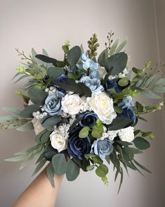 a bouquet of blue and white flowers in someone's hand