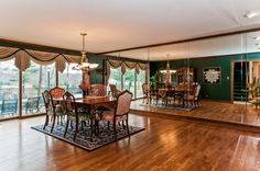 a large dining room with wooden floors and green walls, has an ornate chandelier hanging from the ceiling