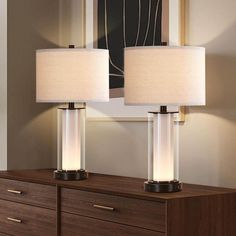 two lamps sitting on top of a wooden dresser