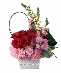 a white vase filled with red and pink flowers