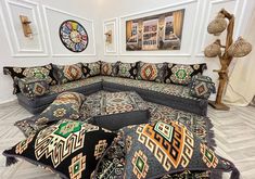 a living room filled with lots of pillows on top of a white floor next to a clock