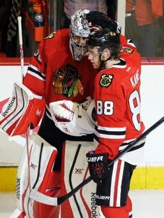 two hockey players hugging each other on the ice