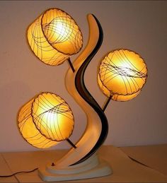 a lamp with three lamps on it sitting on top of a table next to a wall