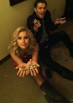 two people are sitting on the floor with their hands in front of them and confetti all around them