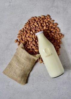 almonds and a bottle of milk on a gray surface with a sack in the foreground