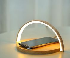 a cell phone is sitting on top of a wooden stand with a light around it