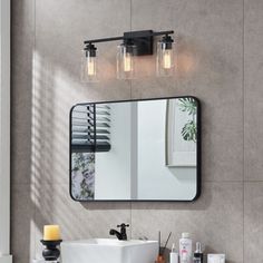 a bathroom with a sink, mirror and lights on the wall next to each other