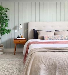 a bed sitting next to a plant in a bedroom