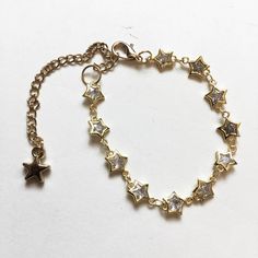 One bracelet, featuring a row of tiny cubic zirconia-filled star shaped gold tone plated brass chain links. Bracelet is adjustable between approximately 6" - 9" long, with a lobster clasp and a gold tone star charm. You will receive one from the photos or identical from the same batch. Gold Metal Bracelets With Star Charm, Gold Metal Bracelet With Star Charm, Gold Metal Chain Bracelet With Star Charm, Gold Star Charm Chain Bracelet, Adjustable Gold Chain Bracelet With Star Charm, Gold Bracelet With Star Charm, Gold Bracelet Jewelry With Star Charm, Gold Chain Bracelet With Star Charm, Gold Crystal Bracelet With Adjustable Chain, Dainty Style