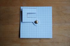 a piece of paper that has been cut into squares with a metal ball on it