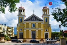 a large yellow church with two towers on it's sides and cars parked in front