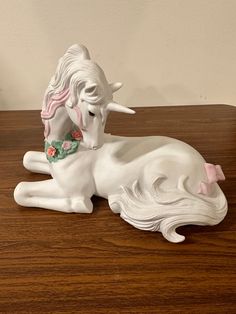 a white ceramic unicorn laying on top of a wooden table